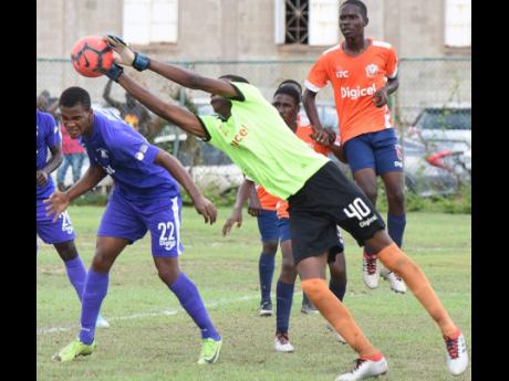 Dunoon Technical High School goalkeeper Ricardo Watson stretches to collect a cross into the box ahead of Kingston College’s Scott McLeod (left) during their aborted ISSA/Digicel Manning Cup game at the Breezy Castle Field in downtown Kingston yesterday. 