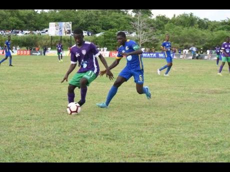 William Knibb Memorial High School’s Deano Thomas (left) is tracked by Cedric Titus High School’s Javel Green in their ISSA/WATA daCosta Cup Group C encounter at William Knibb yesterday. 