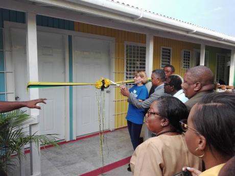 Denise DiBiase is assisted by Michael Stern, deputy board chairman of the Southern Regional Health Authority, as she cuts the ribbon to mark the official opening of the Rock River Health Centre in Clarendon. 