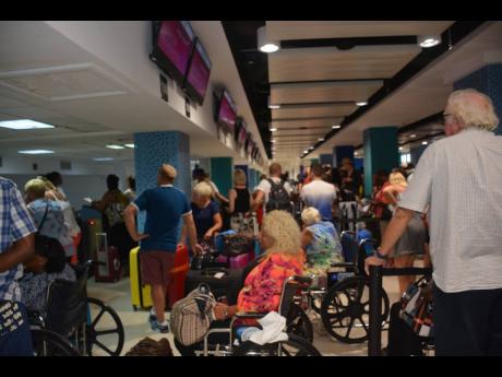 Thomas Cook passengers wait to be processed at the Virgin Atlantic Airways counter at the Sangster International Airport in Montego Bay, St James, yesterday.