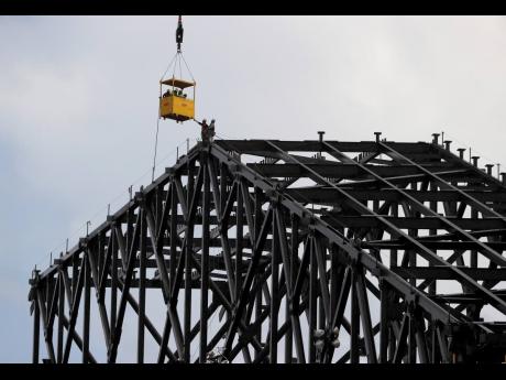 In this July 1, 2019, file photo workers, reach for a transport vehicle lowered to their position at the very top of the roof structure currently under construction atop Globe Life Field as a light rain falls in Arlington, Texas. 