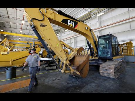In this September 18, 2019, photo, a Puckett Machinery Company technician walks past a new heavy-duty Caterpillar excavator that awaits modification at Puckett Machinery Company in Flowood, Mississippi.