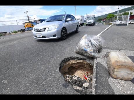 This photo taken on Monday shows a section of Spanish Town Road which has caved in because of recent rainfall in the vicinity of Six Miles, 
St Andrew.
