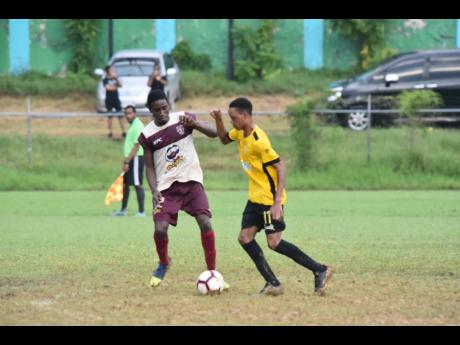 Anchovy High School goalscorer Mark Smith (right) shields the ball from Fabian Grey of St James High School in their Group A match of the ISSA/WATA DaCosta Cup at Jarrett Park on Wednesday.