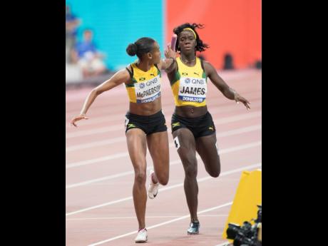 Tiffany James (right) hands the baton to Jamaica teammate Stephenie-Ann McPherson in the transition between the second and third legs of the 4x400m relay final at the IAAF World Championships in Doha, Qatar, yesterday.
