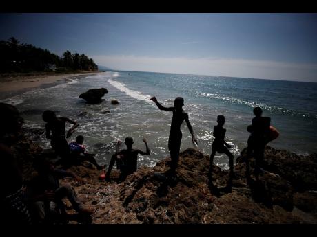 Youths fish with bits of line on the coast near Jacmel, Haiti, Sunday, Oct. 6. Weeks of political turmoil are hitting cities and towns outside the capital of Port-au-Prince especially hard, forcing non-government organisations to suspend aid as barricades cut off the flow of goods between the city and the countryside. (AP)
