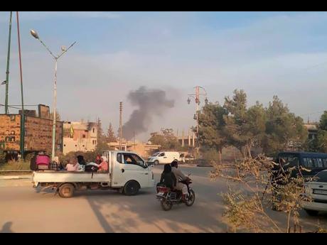 Syrians flee as smoke rises from shelling by Turkish forces in Ras al-Ayn, northeast Syria, yesterday. 