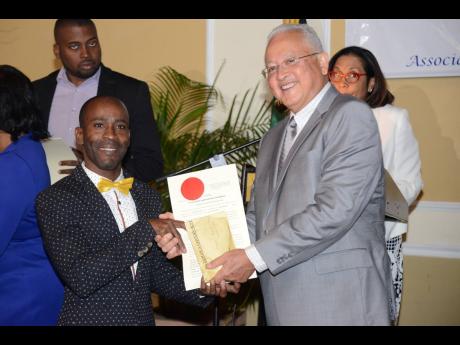 Justice Minister Delroy Chuck (right) presents Jermaine Francis with his certificate and stamp as proof that he is now a registered justice of the peace during a commissioning ceremony held at the Terra Nova All-Suite Hotel in St Andrew on Saturday.