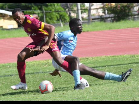 Wolmer’s Boys School’s Jandle Miller (left) is challenged by Greater Portmore’s Rolando Daley during their ISSA/Digicel Manning Cup game at the Stadium East field yesterday.