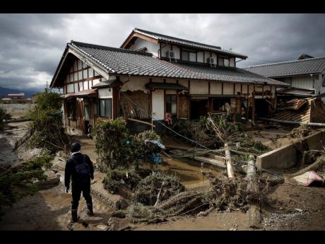 In this photo taken yesterday, a man surveys a home damaged by Typhoon Hagibis in Nagano, Japan. More victims and more damage have been found in typhoon-hit areas of central and northern Japan, where rescue crews are searching for people still missing.