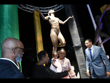 Decorated Jamaican athlete Veronica Campbell-Brown holds her daughter, Avianna Amora Brown, as she chats with Sport Minister Olivia Grange, Prime Minister Andrew Holness (right) and sculptor Basil Watson (left) after the unveiling of a statue in honour of the Olympian at Statue Park inside Independence Park, St Andrew, yesterday.
