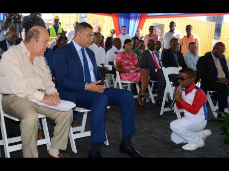 Eleven-year-old Tyrone Thompson serenades Prime Minister Andrew Holness (right) and investor Gordon Tewani during the groundbreaking ceremony for the new BPO company to be rolled out at GTECH Park in Portmore. 