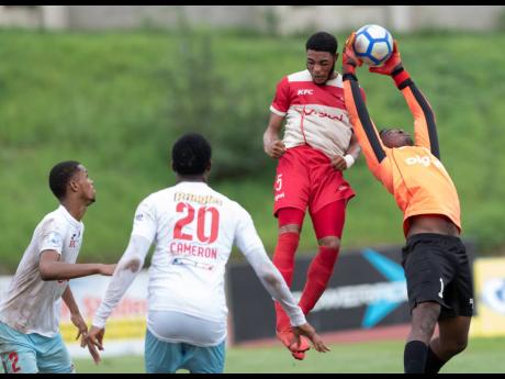 Shaid McLean (left) and Naeem Cameron look on as goalkeeper Orville Smikle (right) of St George’s College snatches the ball ahead of Mona High School’s Loloxley Reid (second right) in their second-round first-leg ISSA/Digicel Manning Cup fixture at Stadium East yesterday. 