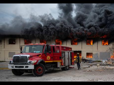 Members of the Jamaica Fire Brigade on the scene of the burning Auto Spares House, located on Lyndhurst Road in the vicinity of Calvary Cemetery, on Tuesday, July 16, 2019.