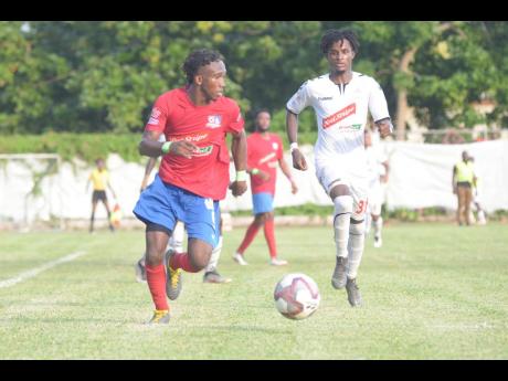 Dunbeholden forward Demario Phillips (left) dribbles as UWI defender Damano Solomon approaches to close him down during their Red Stripe Premier League fixture at the Royal Lakes field in St Catherine yesterday.