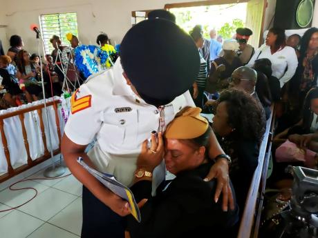 Paulette, widow of Joseph Donaldson, a district constable, is comforted by a member of the police force at the funeral service for both Donaldson and his son, Mikkel, who died tragically weeks apart. The service was held yesterday at the Seaforth Seventh-day Adventist Church in St Thomas.