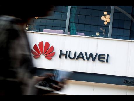 In this July 30, 2019 file photo, a woman walks by a Huawei retail store in Beijing. United States regulators are proposing to cut off funding for Chinese equipment in US networks, citing security threats.