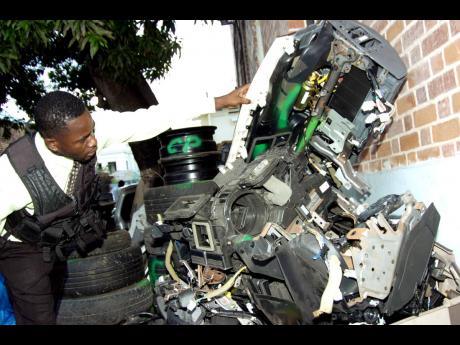 Detective Corporal Desmond Brown of the police Flying Squad inspects stolen motor vehicle parts at their downtown Kingston headquarters in this Gleaner file photo after the team cracked a major car-stealing ring in the Corporate Area.