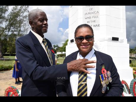 Yvonne Foster smiles brightly as her husband of 33 years, Dwight, straightens her collar during the  Remembrance Day National Memorial Service where World Wars I and II veterans were honoured. The parade was held at National Heroes Park in Kingston on Sunday. 