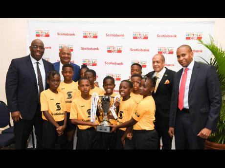 From left: Howard McIntosh, Concacaf senior executive; JFF President Michael Ricketts; Allie McNabb, sports adviser to the minister of sport and David Noel, president and CEO, Scotia  Group Jamaica, pose with students of Holy Family Primary School  at the Concacaf Next Play launch at The Jamaica Pegasus hotel yesterday.