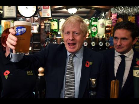 Britain’ Prime Minister Boris Johnson raises a pint of beer as he meets with military veterans at the Lych Gate Tavern in Wolverhampton, England, on Monday, November 11, as part of the general election campaign trail. Britain goes to the polls on December 12. 