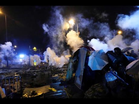 Protesters react as police fire tear gas near Hong Kong Polytechnic University after they gave protesters an ultimatum to leave the campus in Hong Kong, on Sunday, November 17, 2019. Police launched a late-night operation Sunday to try to flush about 200 protesters out of a university campus on a day of clashes in which an officer was hit in the leg with an arrow and massive barrages of tear gas and water cannons were fired.