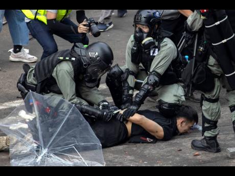 Police detain a protester at the Hong Kong Polytechnic University in Hong Kong on Monday. Hong Kong police fought off protesters with tear gas and batons as they tried to break through a police cordon that is trapping hundreds of them on a university campus. 