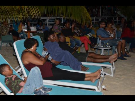 Photos by Janet Silvera 
Locals and tourists enjoy Jamaican movies outdoors in Negril recently.