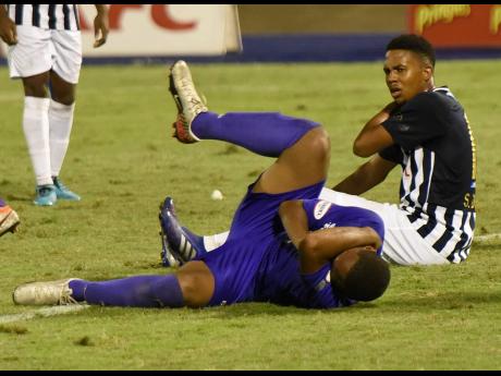 Kingston College’s Khalifah Richards (left) goes down clutching his face after he was slapped by Jamaica College’s Shadane Lopez, who retaliated after being bitten on the shoulder during their ISSA/Digicel Manning Cup semi-final game at the National Stadium last Wednesday night.