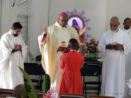 Archbishop of Kingston the Most Reverend Kenneth D. Richards in prayer during 110th anniversary celebration of the Sacred Heart Catholic Church and Donnington Primary School on Sunday. 