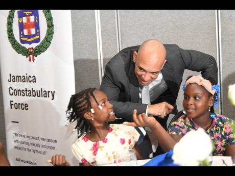 Commissioner of Police Major General Antony Anderson chats with Danielle Pinnock (left) and Jayhanna Jackson at the Jamaica Constabulary Force’s luncheon for children of fallen officers at The Jamaica Pegasus hotel in New Kingston yesterday. The event formed part of the celebrations of Police Week.