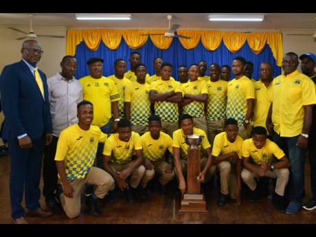 Clarendon College’s DaCosta Cup championship winning team and principal David Wilson (left) pose with the trophy .