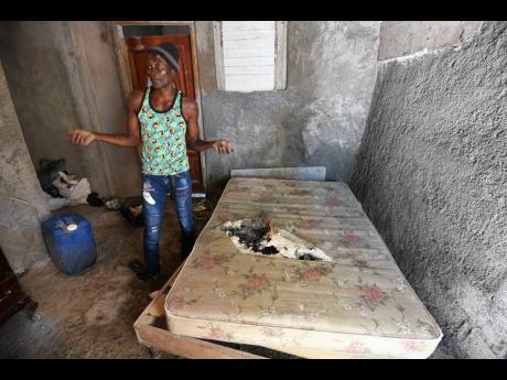Anthony Phillips showing a tattered mattress at his home in Mona Commons, St Andrew.