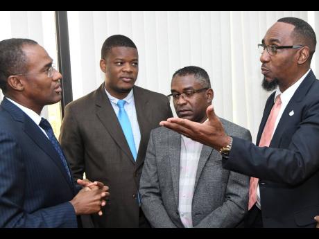 Dr Nigel Clarke (left), minister of finance and the public service, listens pensively to O’Neil Grant (right), president of the Jamaica Civil Service Association, after signing contracts with international consultancy Ernst & Young at the ministry’s Heroes Circle offices on Wednesday. Looking on are Kavan Gayle (second right), president of the Bustamante Industrial Trade Union, and Detective Constable Nigel Murphy of the Police Federation. 