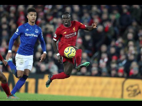 Liverpool’s Sadio Mane (right) controls the ball by Everton’s Mason Holgate during the English Premier League match between Liverpool and Everton at Anfield Stadium, Liverpool, England, yesterday. Liverpool won 5-2.