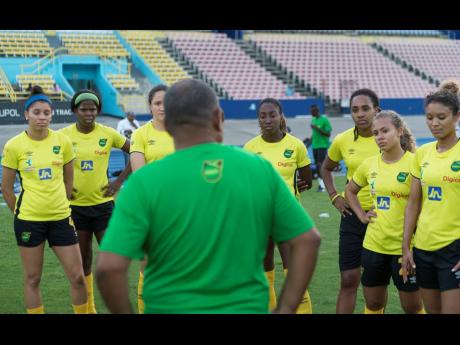 Former Reggae Girlz Head Coach Hue Menzies (back to camera) interacts with several members of the team during a training session held at the National Stadium on May 13, 2019.