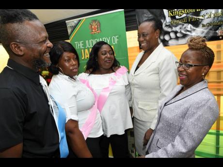 Paula Blake-Powell (right), senior Parish Court judge of the Family Court, and Veronica Poyser (second right), director of court support services, have a light moment with parents Michael Reid (left), Kenisha Barnett (second left), and Anita Morris of the Family Court Parenting School 2019 at an expo on Duke Street, Kingston, on Friday.