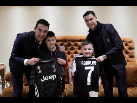 Juventus’ players Cristiano Ronaldo (right) and Gianluigi Buffon (left) pose with Albanian earthquake victims Aurel Lala and Alesio Cakoni in Rome yesterday.