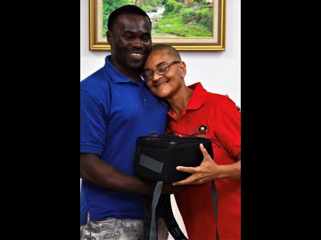 Donnette Ingrid Zacca (right), founder and chair of the Jamaica Photography Society, presents Renardo Raymond with a camera. 