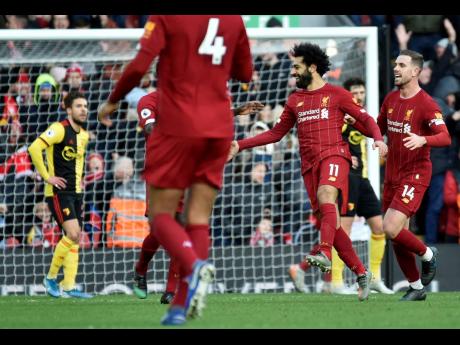Liverpool’s Mohamed Salah (second right) celebrates with teammates after scoring his sides first goal during the English Premier League match between Liverpool and Watford at Anfield stadium in Liverpool, England, yesterday. Liverpool won 2-0.