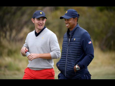 US team player and captain Tiger Woods (right) chats with his player Patrick Cantlay as they walk on the 15th hole during a foursome match during the President’s Cup golf tournament at Royal Melbourne Golf Club in Melbourne yesterday.