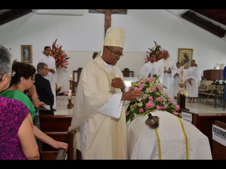 The Most Reverend Kenneth Richards, Archbishop of Kingston, walks with the censer around the coffin bearing the body of Beverley Lopez during the funeral held at the Stella Maris Roman Catholic Church on Saturday.
