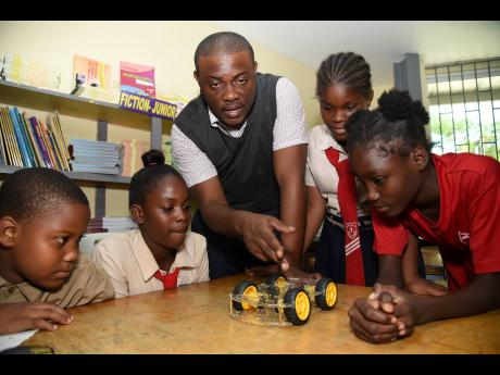 Instructor Wayne Thompson is flanked by Bull Bay Infant and Primary students (from left) Demarco Johnson, Daneshia Ewin, Lataya Sewell, and Kerry-Ann Walters during a robotics session.