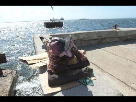 Walter Duncan, popularly known as Ras Emmanuel, demonstrates how he has been sleeping on a ledge by the Kingston waterfront at nights since June this year.