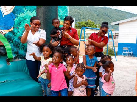 Team members of the ICWI Group (from left) broker representative Kayla Lewis-Thomas, chairperson of the ICWI Group Foundation Valerie Reynolds, and Broker Representative Simone Reid-Pryce play along with students of the Little Lighthouse Basic School as they sing Christmas carols during their fair on Monday. 