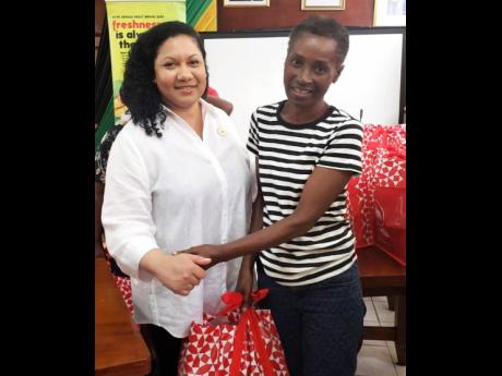 Edith Chin, co-owner and director of Juici Patties, hands a Christmas care package to May Pen Market vendor Verna Lewin at the Clarendon Municipal Corporation on Thursday, December 19.