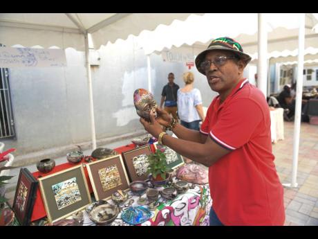 David Dunn, potter, explains the concept for some of his pieces on display at the Kingston Creative Artwalk Grand Market along Water Lane in downtown Kingston yesterday.