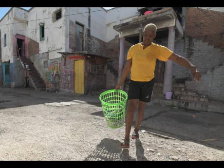 Marcia Johnson, 55, prepares to hang out clothes to dry at premises located on West Street in downtown Kingston. She is one of more than 80 people squatting in deplorable conditions on the property.