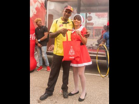 Winner of the Coca-Cola Christmas Truck Tour’s Drinking Competition, Desmond Chambers, is gifted with his prize by Santa’s Little Helper, Tamra Durrant during the final stop of the Tour in Half-Way-Tree on December 14.
