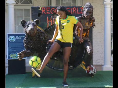 Reggae Girlz captain Konya Plummer juggles a football in front of a statue of her that was unveiled at the S Hotel/Usain Bolt Tracks and Records property on Sunday.